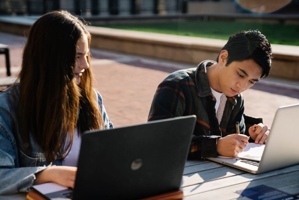 Students using laptops outdoors for study session